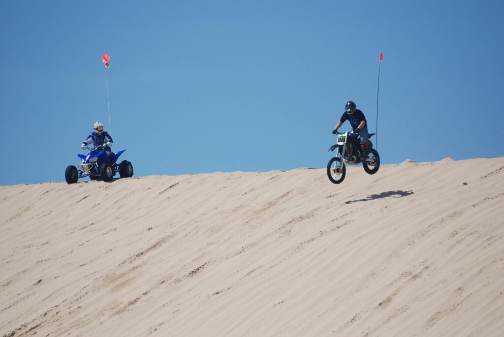 Person riding a dirt bike on Pismo Beach with ocean waves in the background.