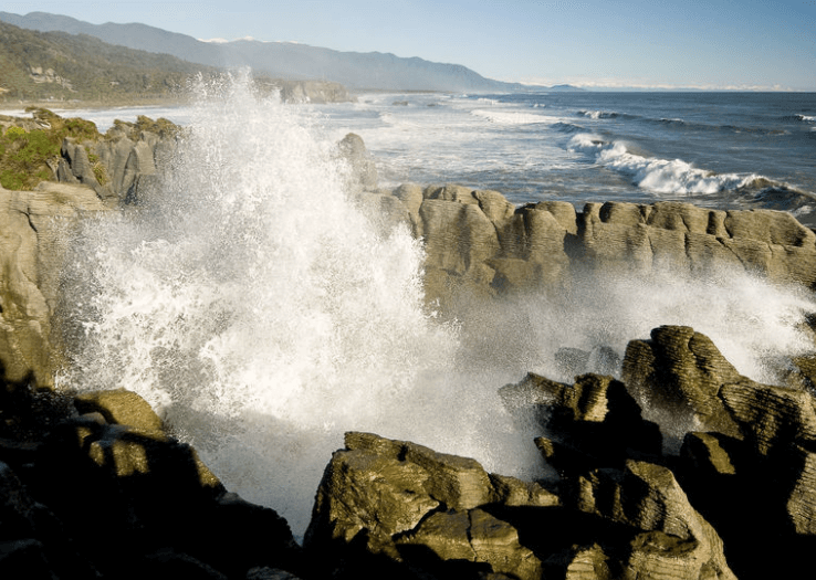 Waves crashing on rocks at beach, West Coast. 